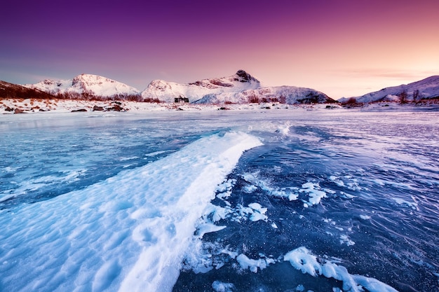 Cume da montanha e gelo na superfície congelada do lago Paisagem natural nas ilhas Lofoten Noruega Água e montanhas durante o pôr do sol