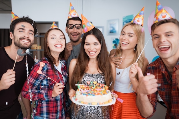 La cumpleañera sostiene un pastel con velas.