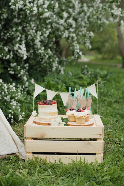 Cumpleaños de verano, decoración en el jardín. Pasteles de cupcake con bayas en una caja de madera.