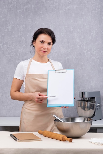 Cumplimiento de las normas sanitarias en las cocinas de los restaurantes Mujer en la cocina tiene documentos en sus manos Marco vertical