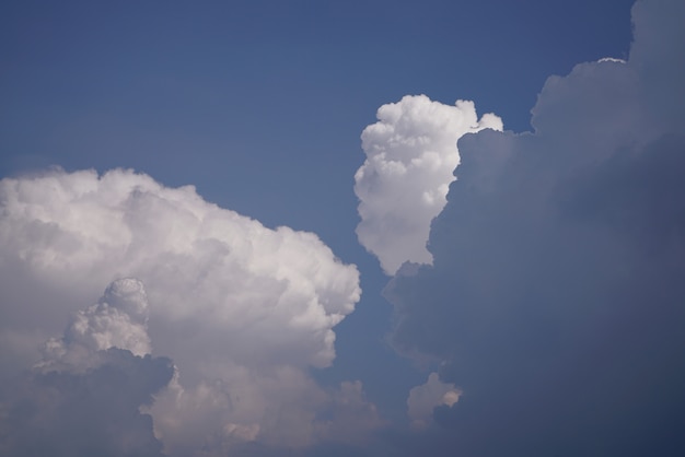 Cumulonimbus, Nimbostratus und flaumige Cumuluswolken am blauen Himmel.