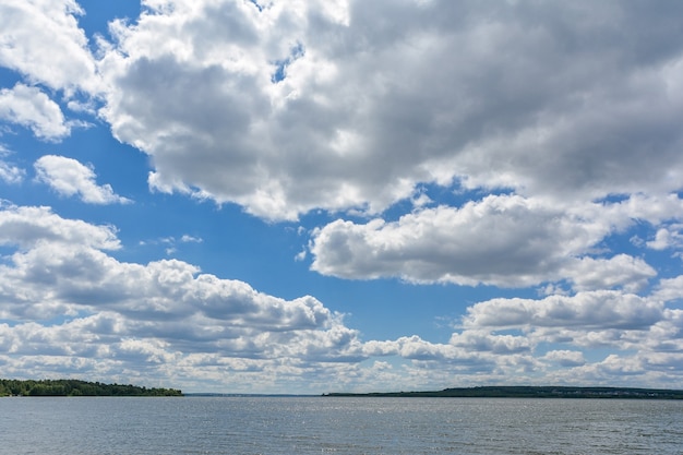 Cúmulos brancos no céu azul acima do lago.