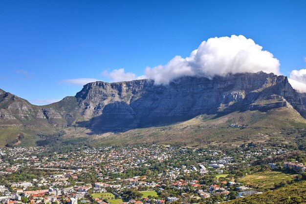 Cumulus-Wolken bilden sich über Lions Head Mountain vor blauem Himmel mit copyspace Panoramablick auf die Landschaft der grünen Berge mit Vegetation rund um eine Stadt in Kapstadt, Südafrika