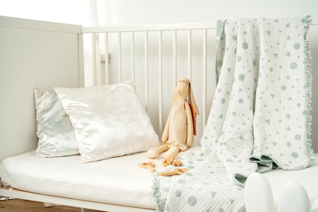 Foto cuna de bebé blanca de madera y conejo de juguete de cerca