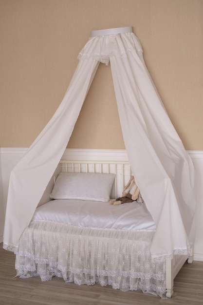 Cuna con biombo y almohadas blancas en una habitación beige