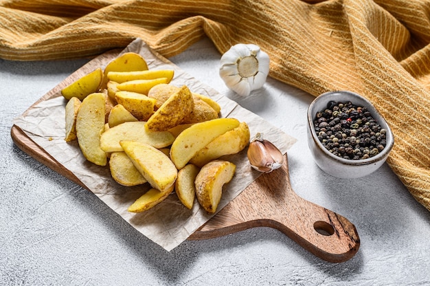 Cuñas de papa congeladas sobre una tabla para cortar. receta de patatas fritas. fondo blanco. vista superior.