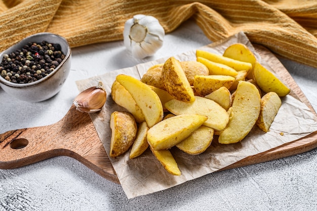 Cuñas de patata congelada sobre una tabla para cortar madera