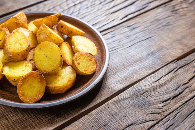 Cuñas de patata frita sobre un fondo de madera oscura.