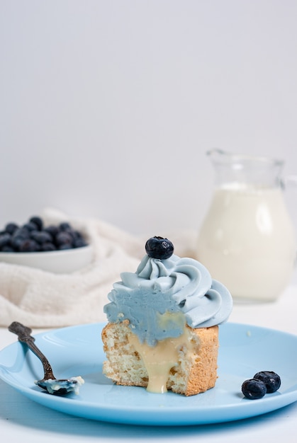 Cupcake azul cortado por la mitad con el relleno de limón fluye sobre una placa azul