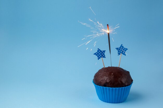 Cupcake con bengala sobre un fondo azul.