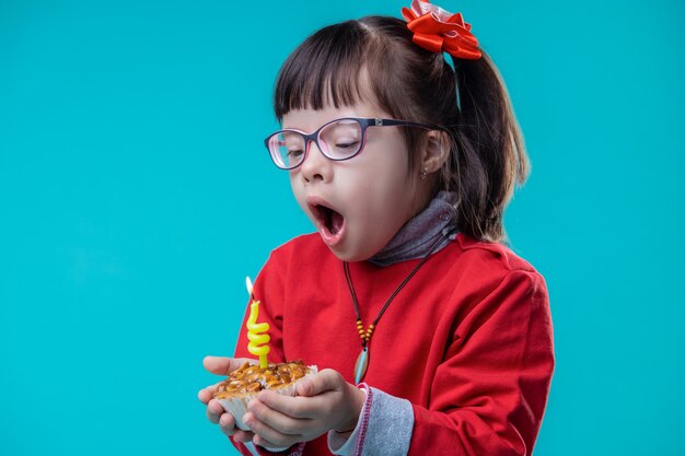 Cupcake beobachten. Neugieriges hübsches Mädchen, das gelbe Kerze ausbläst, gestapelt im kleinen Cupcake