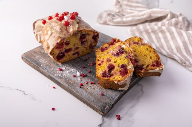 Cupcake caseiro e duas peças com cranberries e açúcar de confeiteiro em uma tábua de madeira acesa