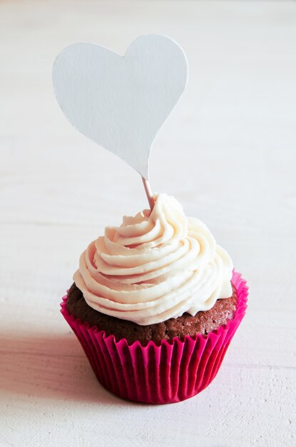 Cupcake de celebración para el día de San Valentín en mesa de madera blanca con corazones.