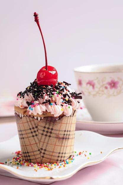 cupcake con cereza encima y una taza de té