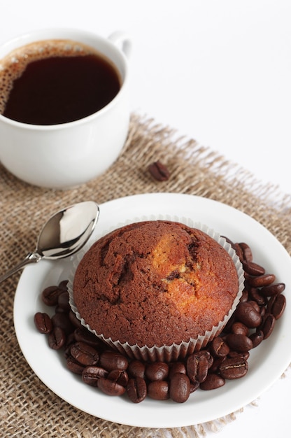 Cupcake de chocolate con taza de café caliente sobre fondo de arpillera