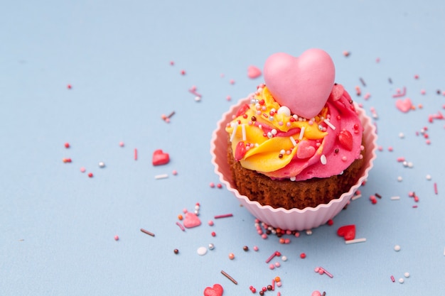 Cupcake com creme e corações - bolos de férias para o dia dos namorados. Superfície azul. .