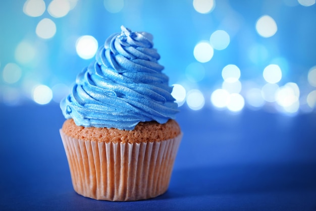 Foto cupcake com glacê de creme azul sobre fundo brilhante