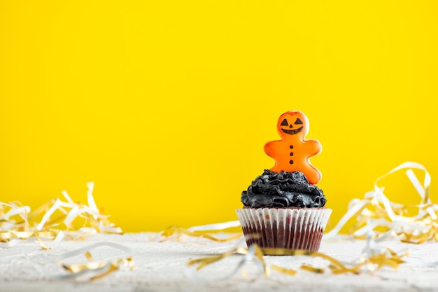 Cupcake com pão de gengibre em fundo amarelo Doces para celebrar o bolo de Halloween para o Halloween