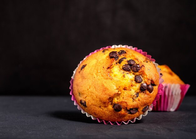 Cupcake com pedaços de chocolate em superfície escura