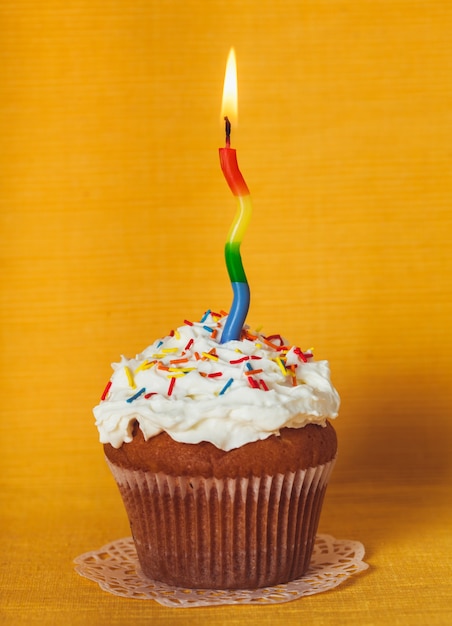 Cupcake com uma vela acesa em guardanapo amarelo