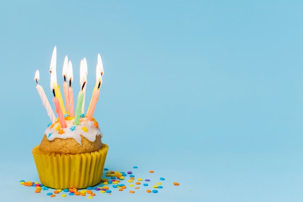 Cupcake com velas acesas em fundo azul com espaço de cópia