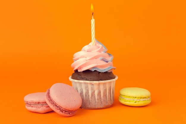 Cupcake com velas de aniversário em fundo laranja