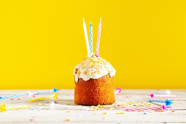Cupcake comemorativo com velas em um fundo amarelo. Decorações para um aniversário ou feriado.