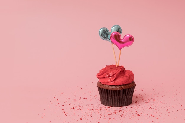 Cupcake con crema roja y decoración de dos corazones para banner de San Valentín con espacio de copia