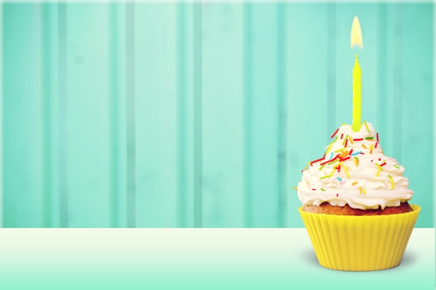 Cupcake con crema y velas sobre fondo de color brillante