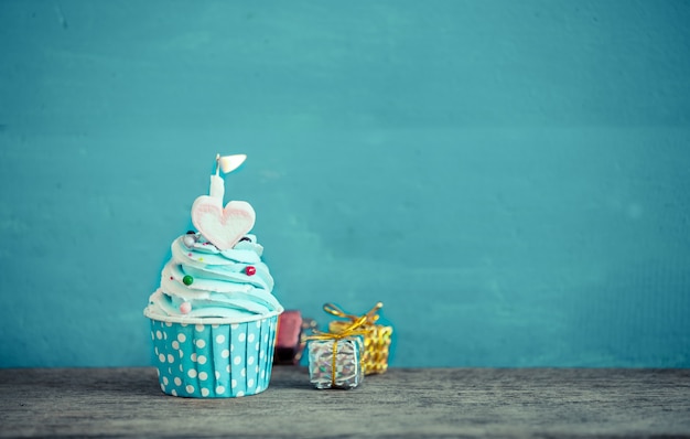 cupcake de cumpleaños con forma de corazón dulce de malvavisco y vela sobre fondo azul