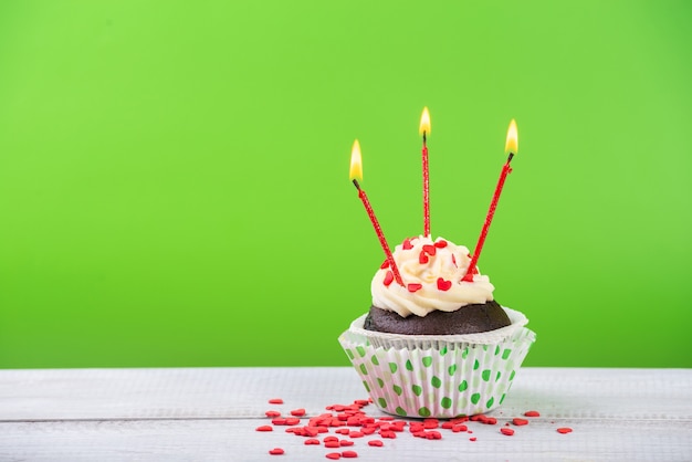 Cupcake de cumpleaños en verde con velas multicolores.