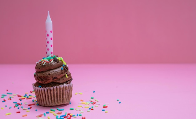 Cupcake de aniversário com vela no espaço de cópia de fundo rosa pastel