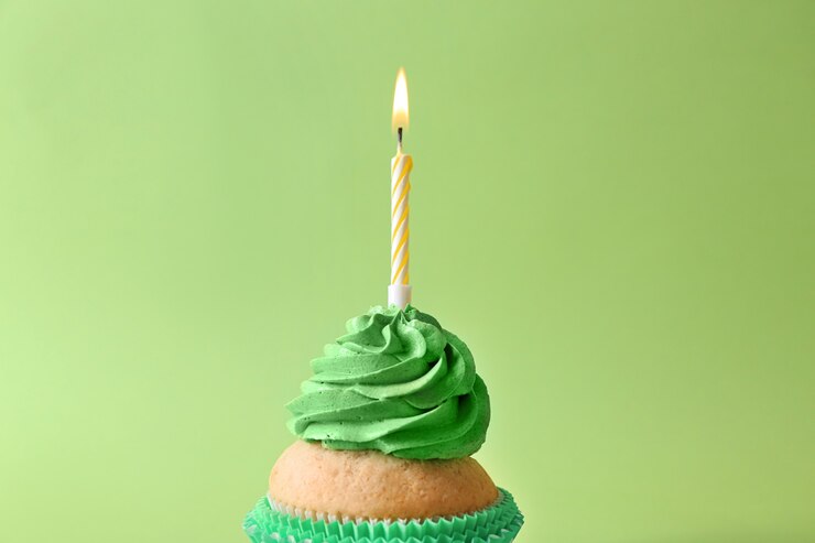 Foto cupcake de aniversário delicioso com vela acesa na cor de fundo