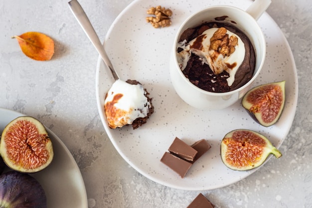 Cupcake de chocolate com queijo creme ou ricota com molho de caramelo em uma caneca de cerâmica branca. Comida de outono ou inverno de conforto.