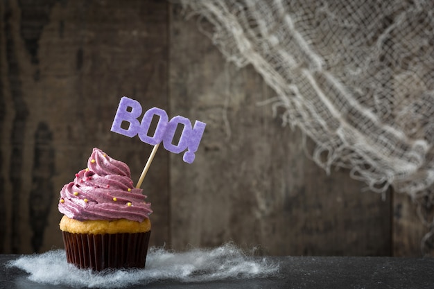 Cupcake de Halloween roxo em fundo preto. Copie o espaço