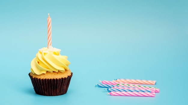 Cupcake e vela em um fundo azul.