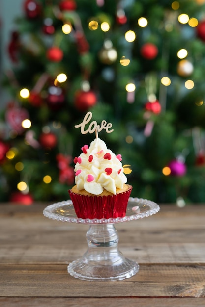 Cupcake em expositor em fundo de madeira e árvore de Natal fora de foco em segundo plano Copiar espaço Foto vertical