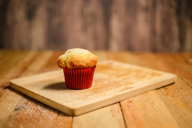 Cupcake isolado na mesa de madeira. Cupcake em molde de papel vermelho.