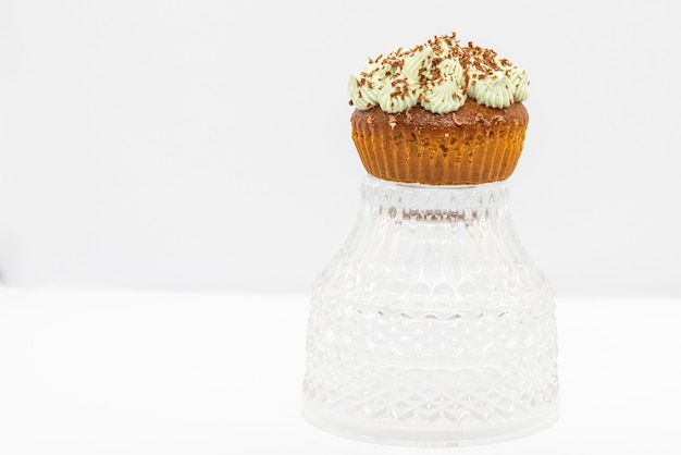 Cupcake luxuoso, com creme de manteiga de menta e chocolate â € “em prato de cristal, fundo branco