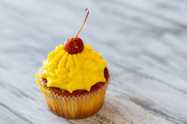 Cupcake mit gelber Sahne. Dessert auf grauem Hintergrund. Rezept für gute Laune. Essen und genießen.