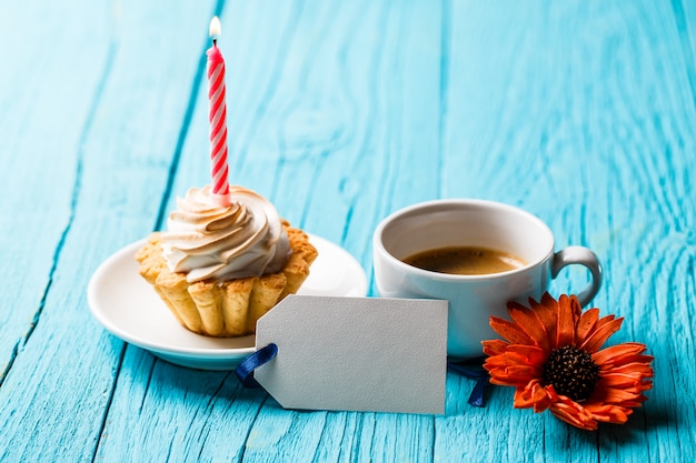 Cupcake mit Kerze nahe Kaffee und Blume