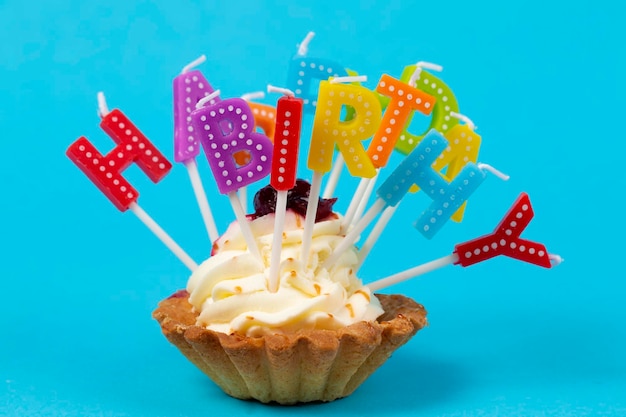 Cupcake mit regenbogenfarbenen Kerzen zum Geburtstag mit der Aufschrift Happy Birthday