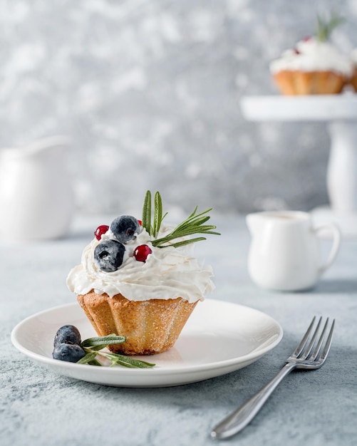 Cupcake (Muffin) mit Blaubeere und Rosmarinbuttercreme auf einem grauen Foto. Hochwertige, hausgemachte Backwaren