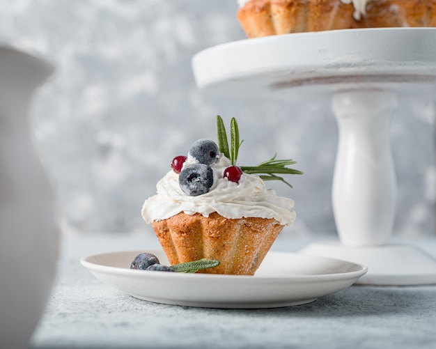 Cupcake (Muffin) mit Blaubeere und Rosmarinbuttercreme auf einem grauen Foto. Hochwertige, hausgemachte Backwaren