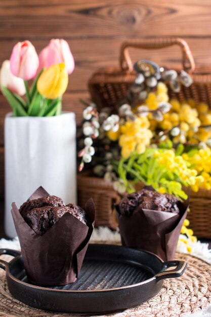 Cupcake-Muffin mit Schokolade auf weißem Hintergrund mit einem Bouquet von Mimosa Glückwunsch zu der Postkarte zum Internationalen Frauentag