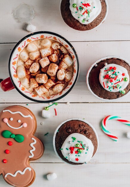 Cupcake de Navidad de chocolate con cobertura de azúcar de colores y taza de cacao con malvavisco