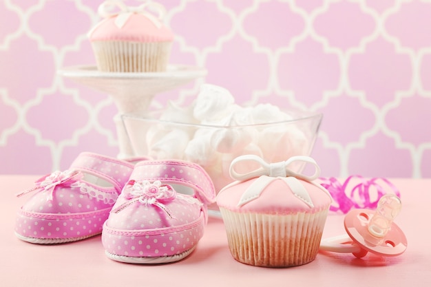 Foto cupcake saboroso com laço e sapatilhas de bebê, chupeta