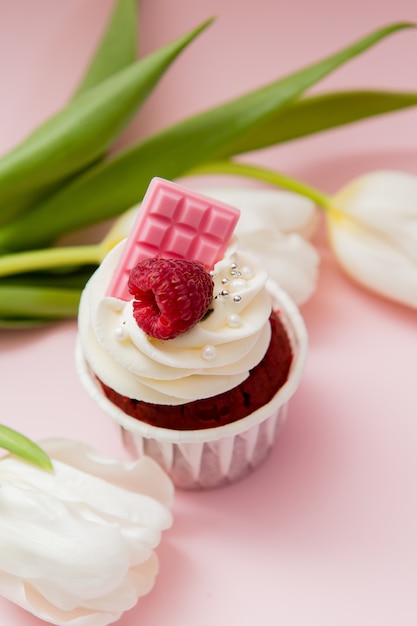 Cupcake und weiße Tulpen auf einer rosa Oberfläche, Platz für Text