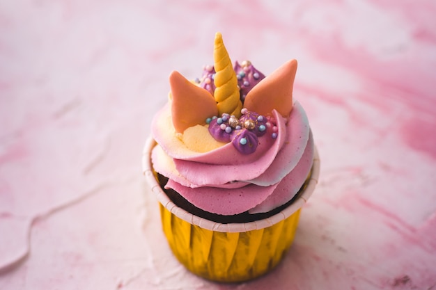 Cupcake de unicornio arcoiris en una taza amarilla