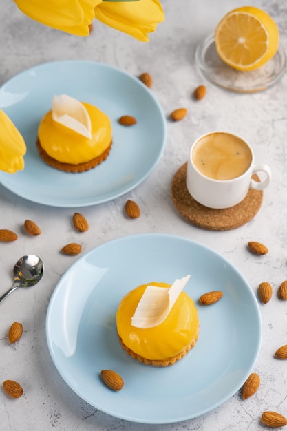 Cupcakes amarelos e xícara de café com tulipas amarelas em fundo de concreto Sobremesa saborosa da manhã